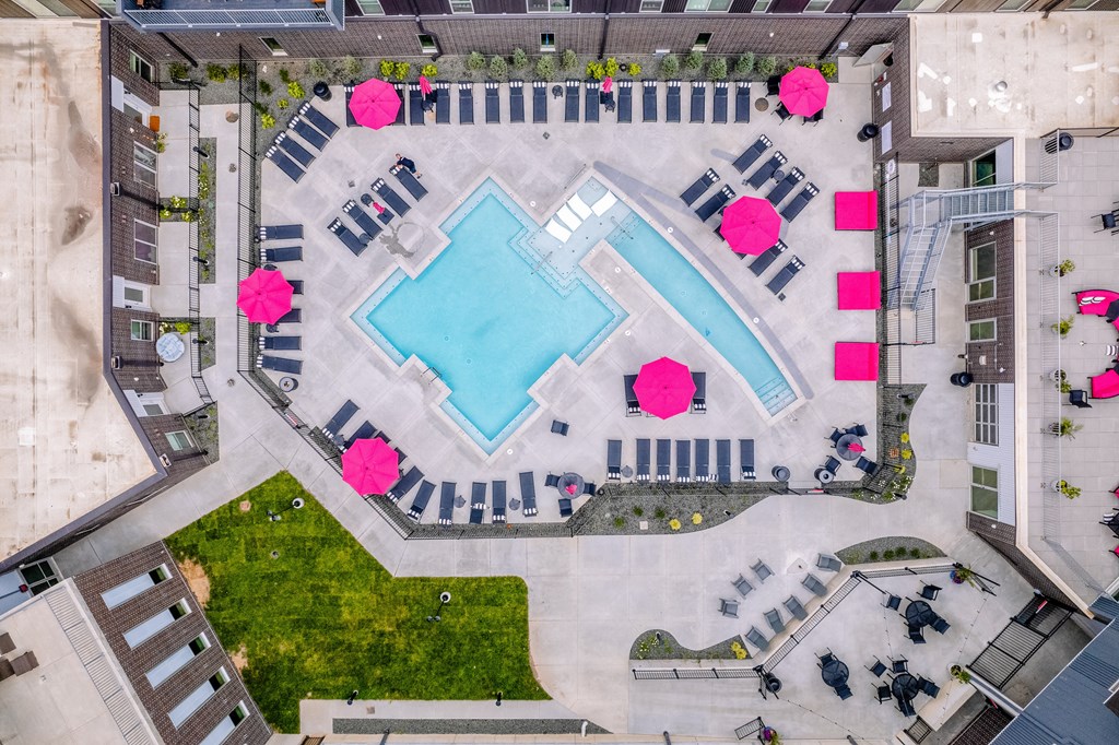 an aerial view of a pool surrounded by buildings and grass