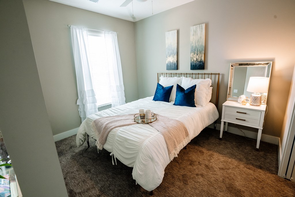 a bedroom with a white comforter and blue pillows