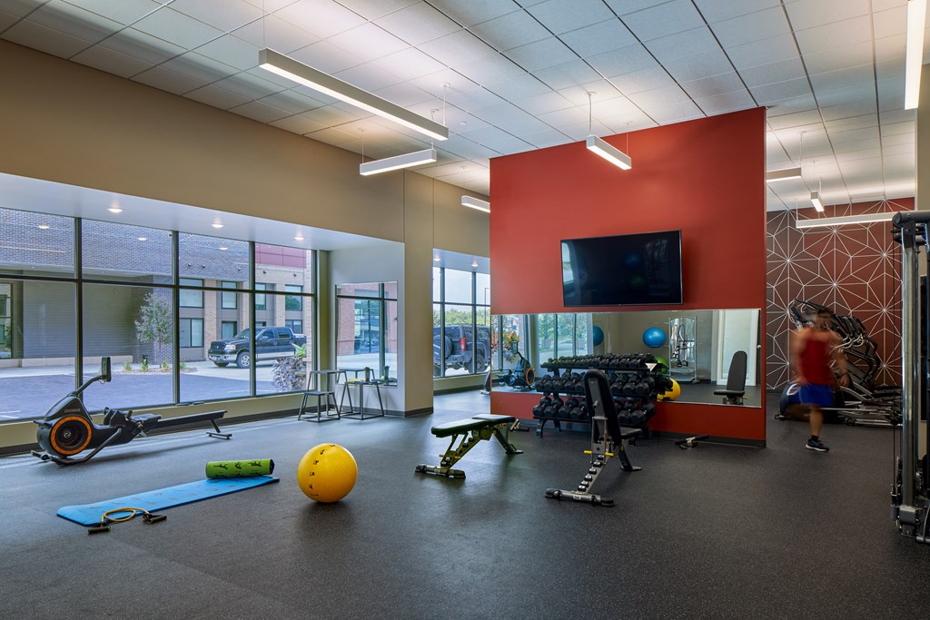 a workout room with weights and cardio equipment and a television