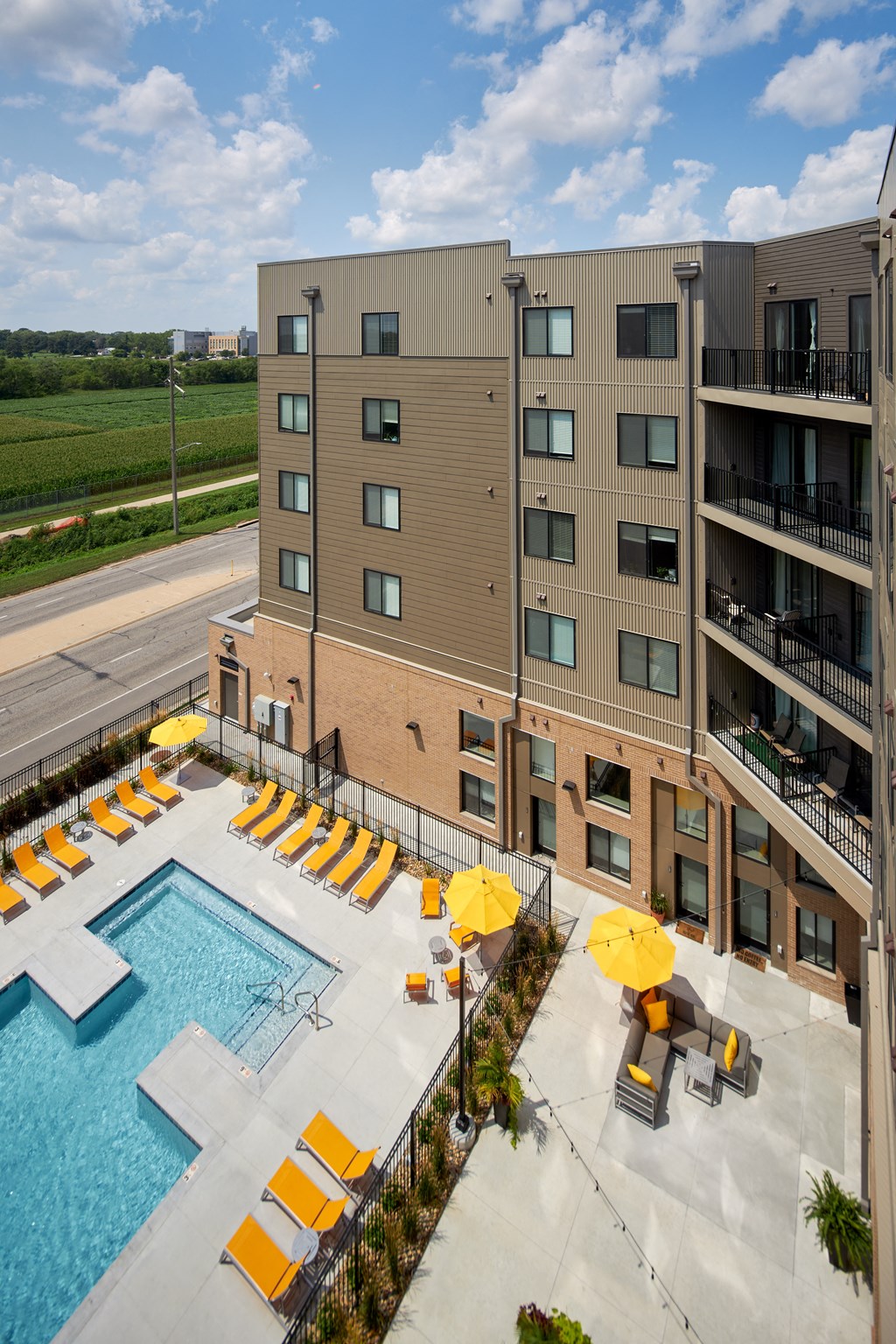 an aerial view of a swimming pool with yellow umbrellas and a hotel building
