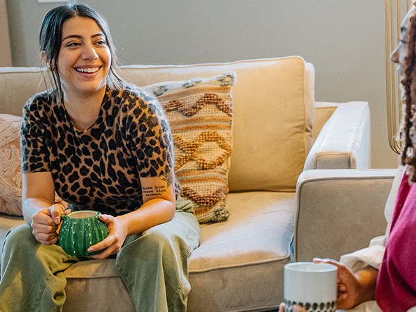 a woman sitting on a couch holding a green cup