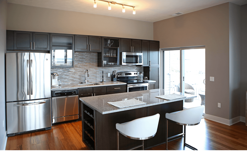 a kitchen with stainless steel appliances and an island with white chairs