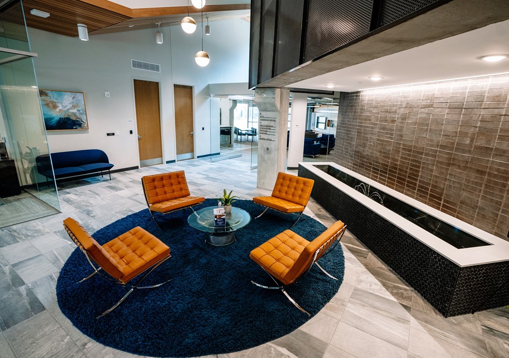 a lobby with orange chairs and a blue rug