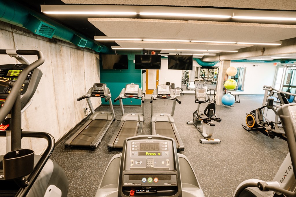 a gym with cardio equipment and weights on the floor
