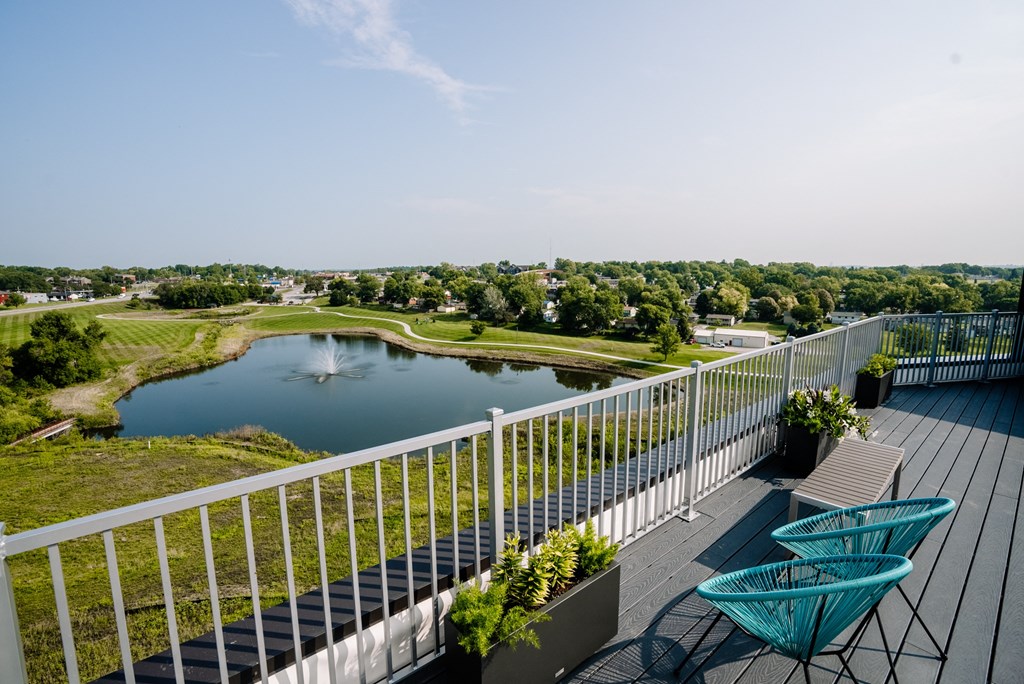 a balcony overlooking a pond and a park with chairs on it