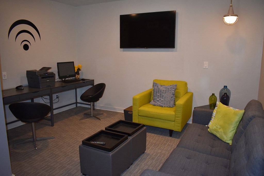 a living room with a couch and a chair and a desk with a television