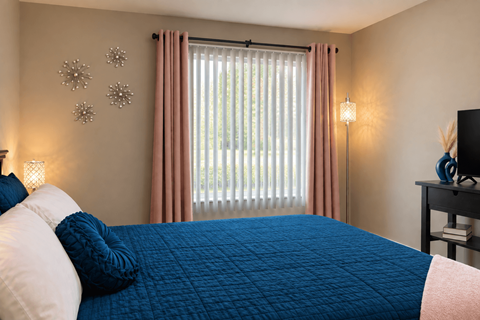 A bedroom with a blue comforter and pink pillows.