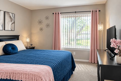 A bedroom with a blue bedspread and pink bedding.