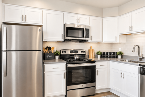 A modern kitchen with white cabinets and stainless steel appliances.