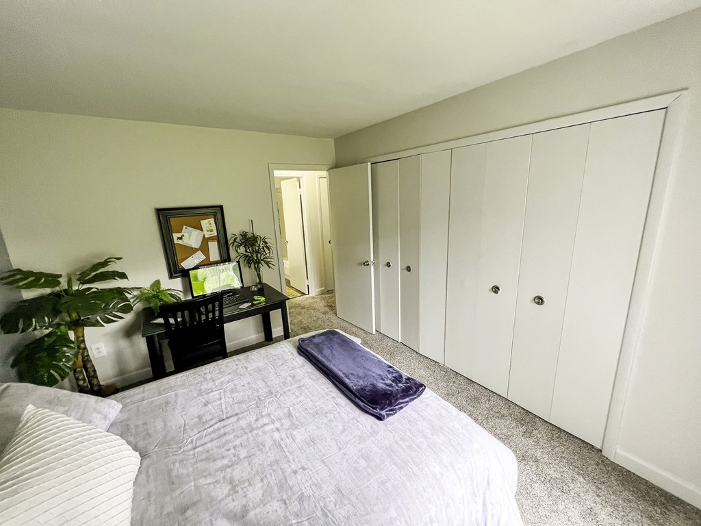 a bedroom with white closets and a bed with a blue blanket