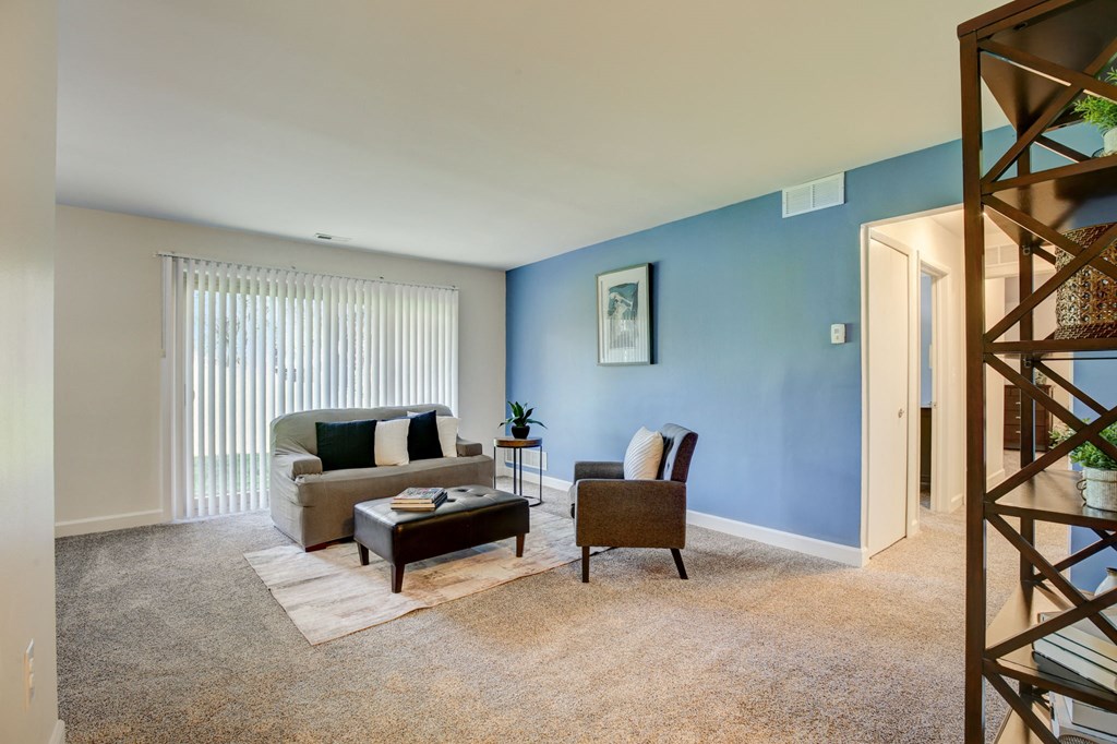 a living room with a blue wall and a couch - Maple Place Apartments