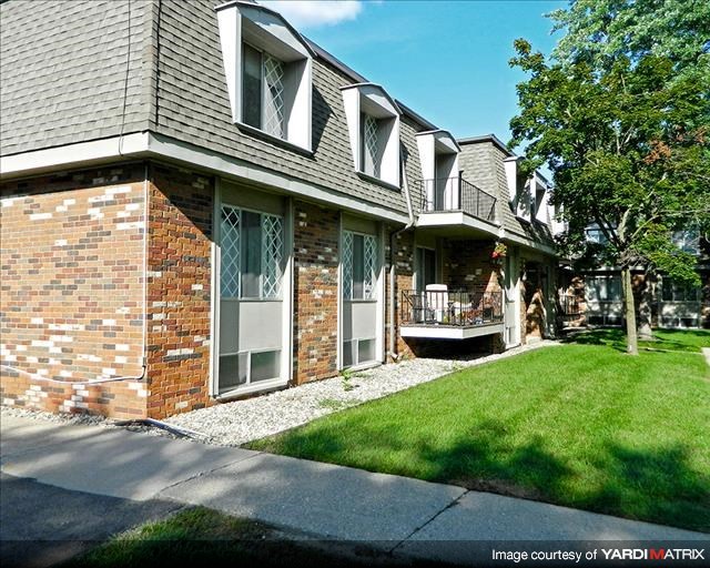 a brick house with a porch and a lawn