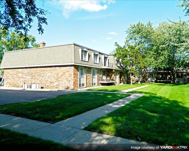 a brick house with a lawn and trees