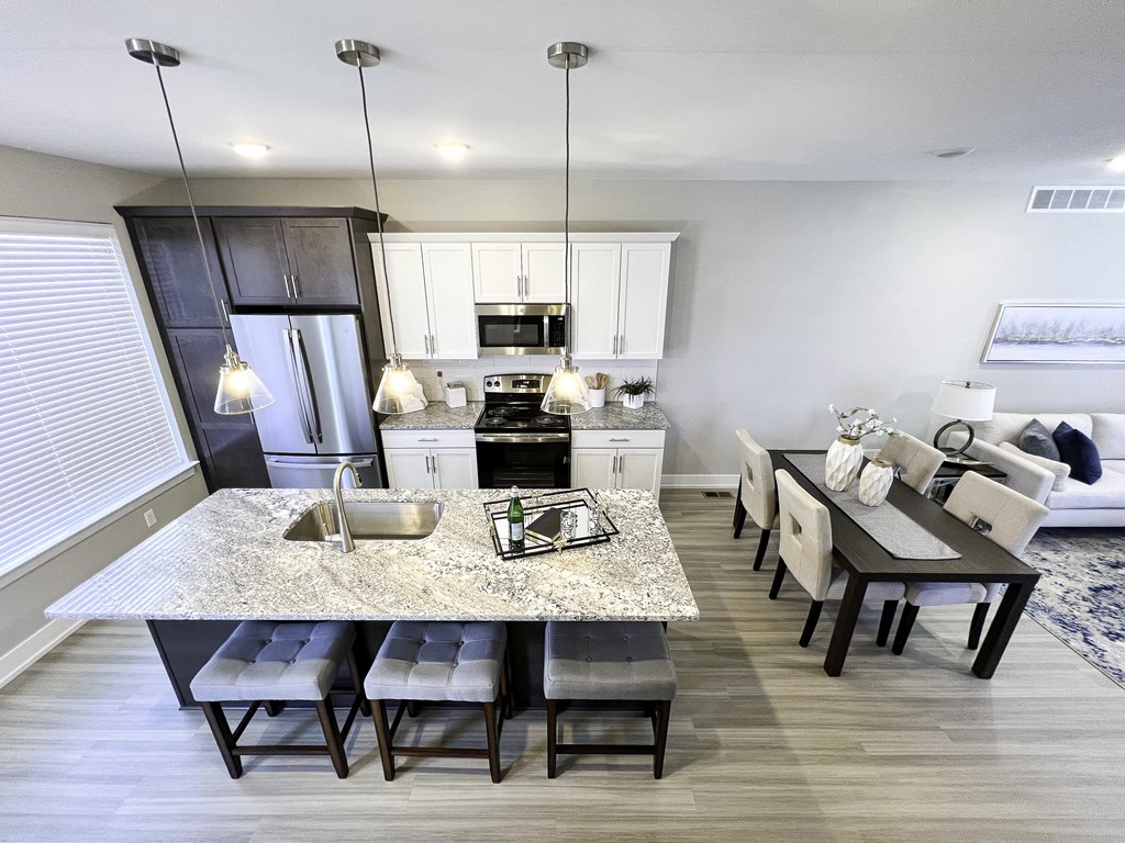 an open kitchen and dining room with a marble counter top and a table with chairs