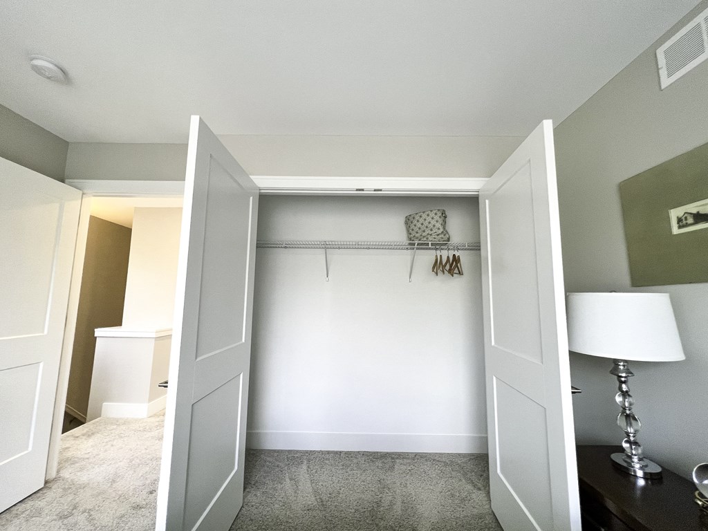 an empty closet in a home with a white wall and white closet doors