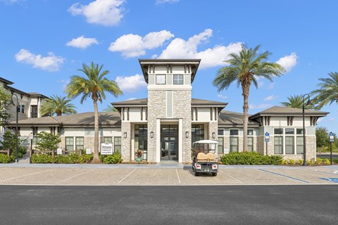 A golf cart is parked in front of a building with palm trees.