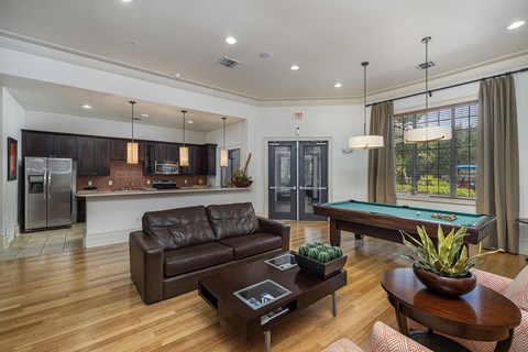 A modern living room with a pool table and a refrigerator.