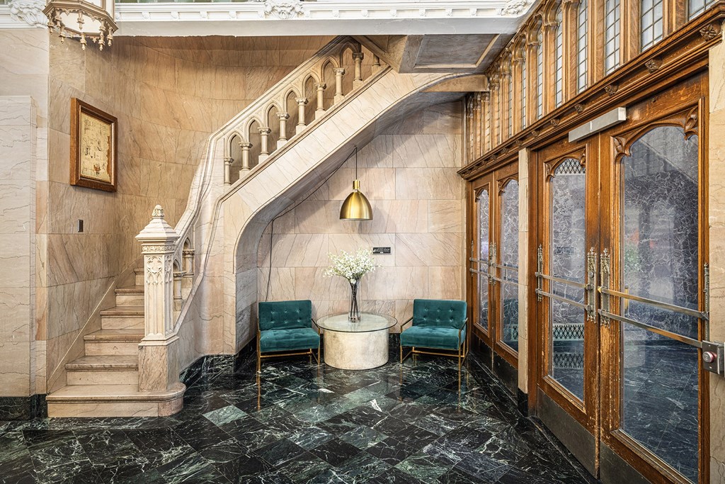 A marble staircase with a green chair and a table with a vase of flowers.