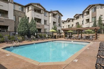 Resort-style swimming pool with surrounding sundeck - First and Main Apartments