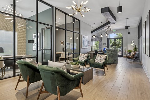 A modern living room with green velvet chairs and a glass wall.