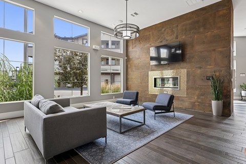 A modern living room with a grey couch, a black chair, a wooden wall, and a flat screen TV.