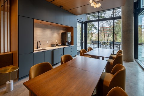A long wooden table is surrounded by chairs in a modern kitchen.