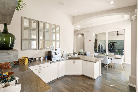 A kitchen with white cabinets and a green vase on the counter.