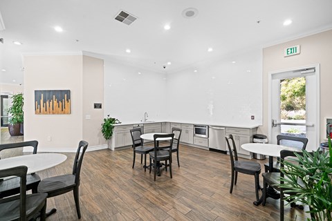 a community room with tables and chairs and a kitchen