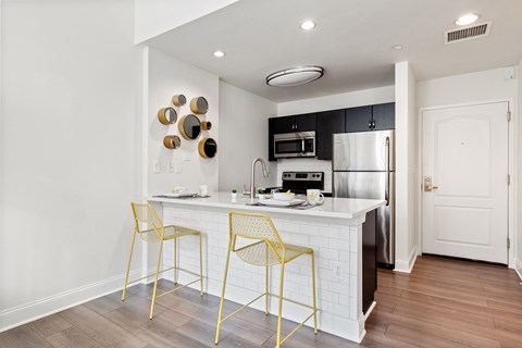 a white kitchen with yellow bar stools and a stainless steel refrigerator