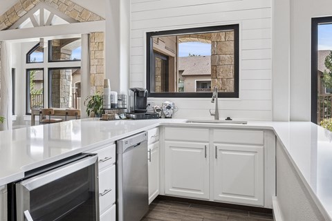 A modern kitchen with white cabinets and a large window.