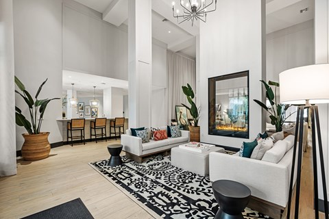 A living room with a white couch, a black and white rug, and a painting on the wall.