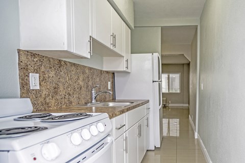 A kitchen with a white stove and white cabinets.