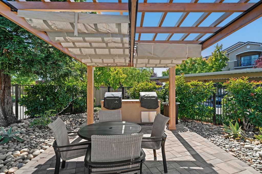 a patio with a pergola and a table and chairs