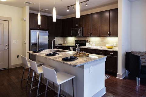 a kitchen with a large island with white chairs