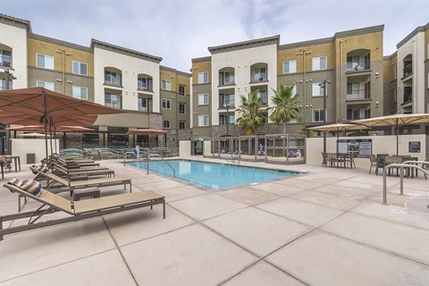 Resort-style swimming pool with lounge and cabana seating - Talavera Apartments