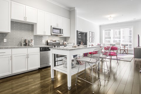 A kitchen with white cabinets and a marble island.