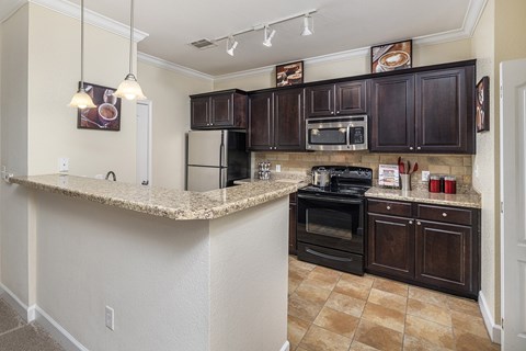 A kitchen with brown cabinets and a granite counter.