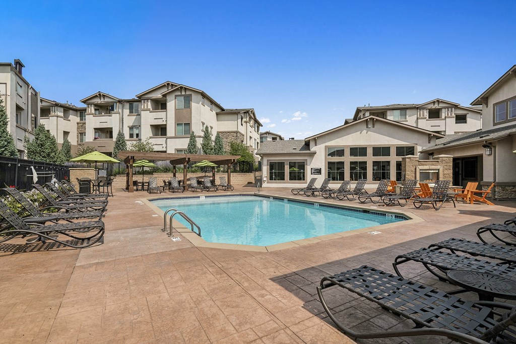 Resort-style swimming pool surrounded by lounge chairs - First and Main Apartments