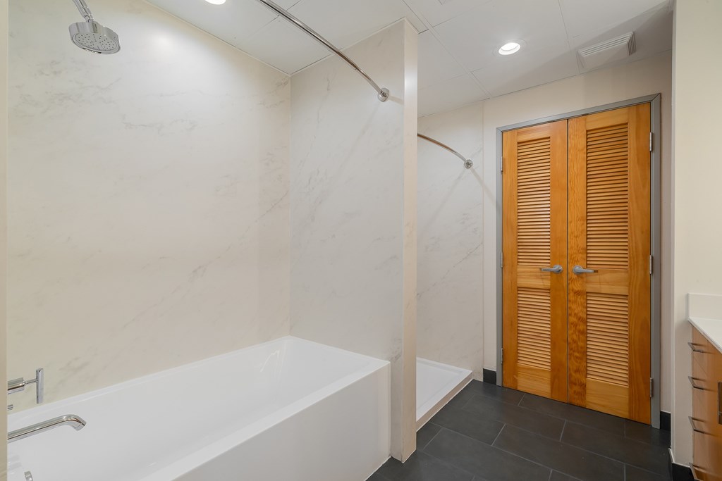 A white bathtub in a bathroom with a wooden door.