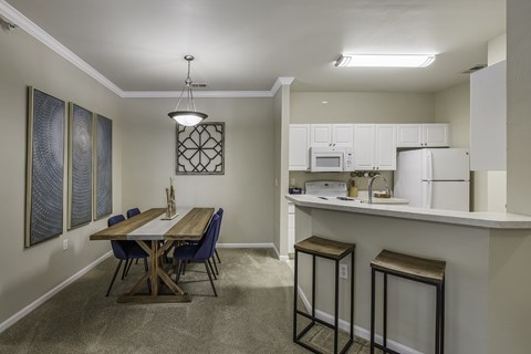 A kitchen area with a table and chairs.