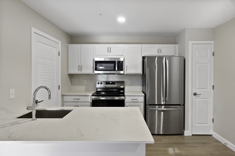 A kitchen with a white counter top and stainless steel appliances.