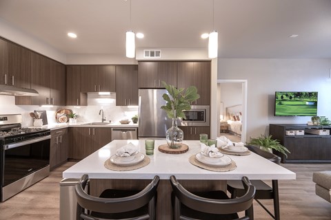 A modern kitchen with a dining table set for two.