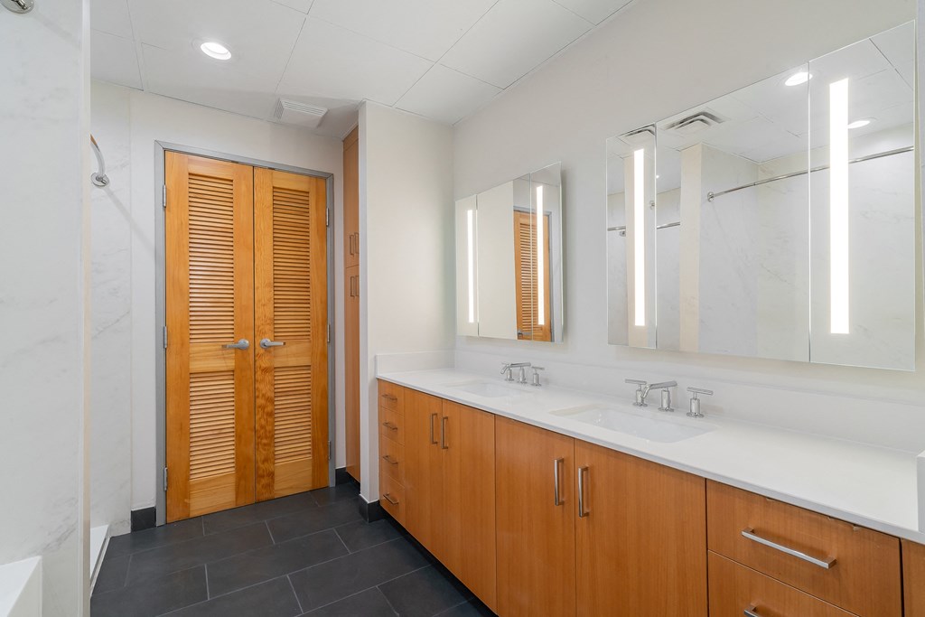 a bathroom with two sinks and a shower and wooden doors
