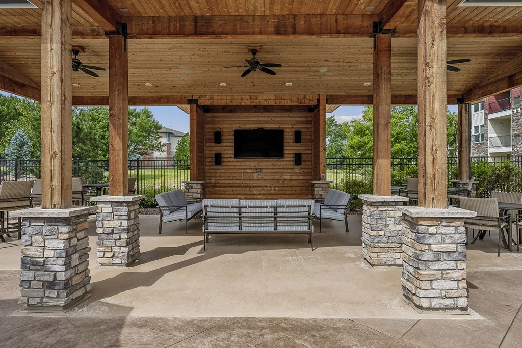 a covered patio with stone pillars and a fireplace
