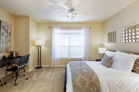 a bedroom with a bed and a desk and a ceiling fan