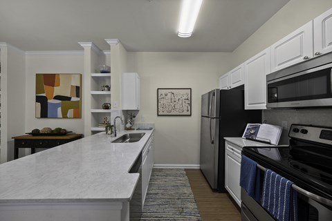 A kitchen with white cabinets and a marble countertop.