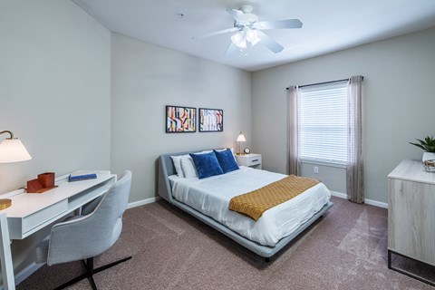 A bedroom with a bed, desk, and chair.
