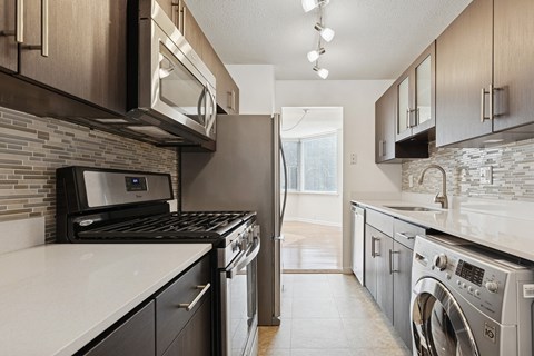 A modern kitchen with dark brown cabinets and stainless steel appliances.