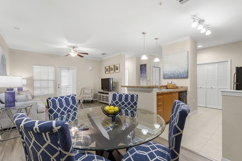 A modern dining room with a glass table and blue chairs.