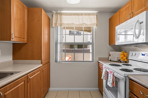 a kitchen with white appliances and wooden cabinets and a window